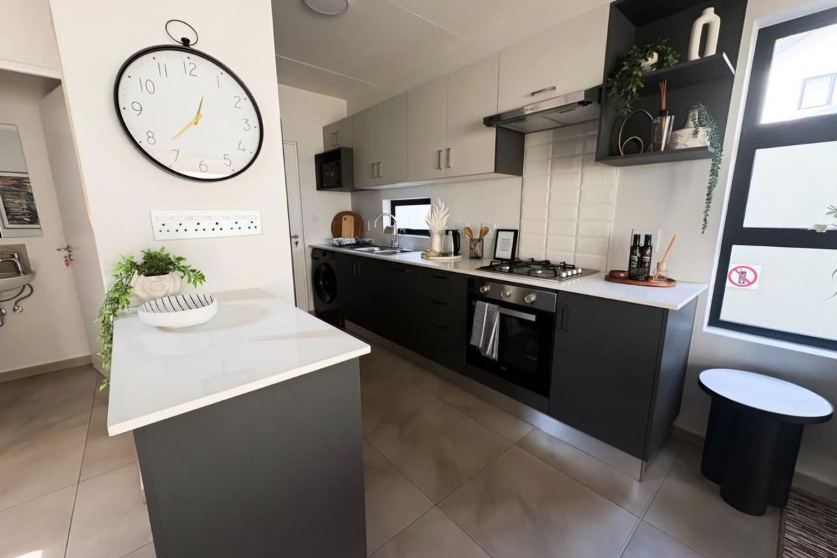 Modern kitchen featuring sleek dark and light cabinetry, stone countertops, gas hob, integrated oven, and subway tile backsplash with tiled flooring.