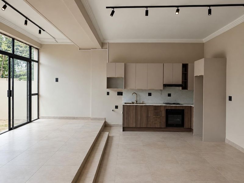 Modern open-plan kitchen and living area featuring sleek cabinetry, integrated appliances, tiled flooring, and large sliding glass doors leading to the exterior.