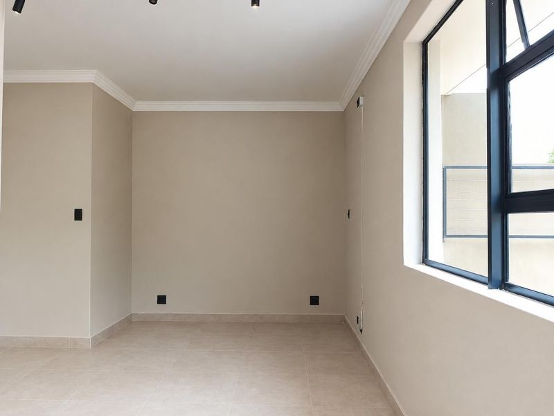 A bright, empty bedroom featuring neutral tiled flooring, modern aluminium window frames, and clean coving detail, ready for personalization.