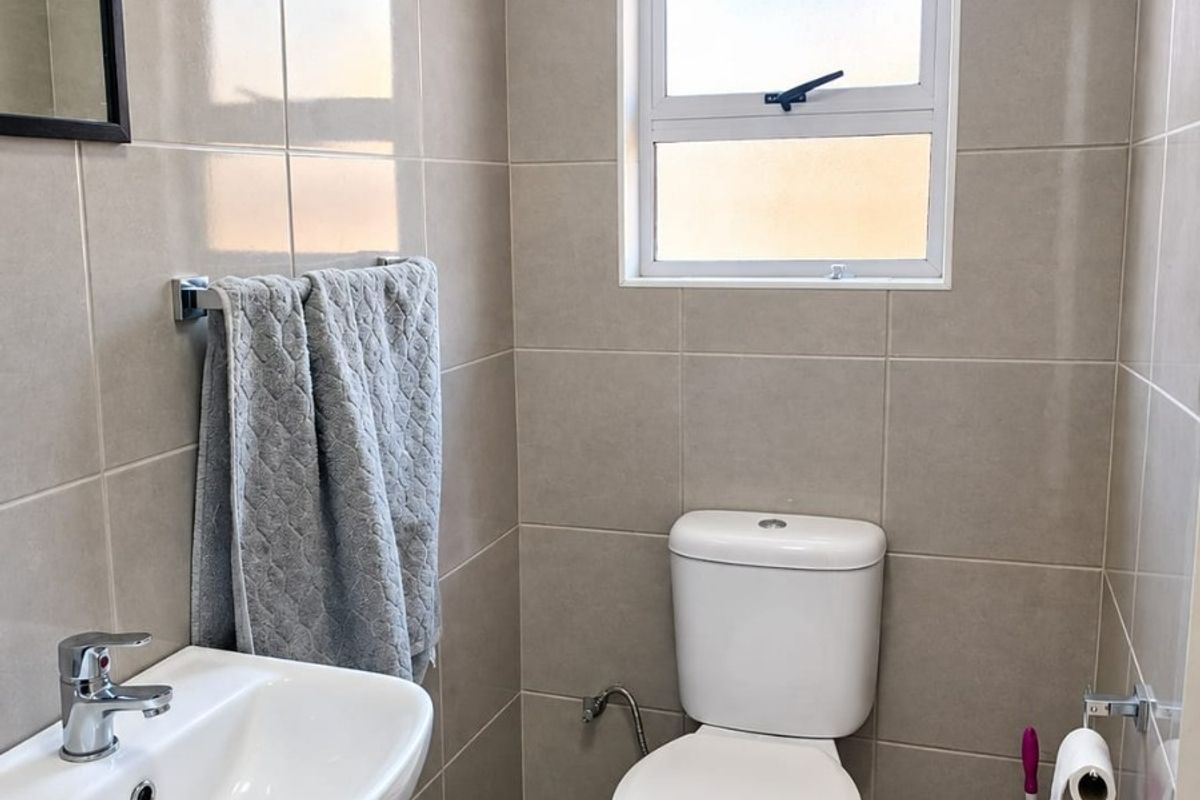 A clean and well-maintained bathroom featuring neutral ceramic wall and floor tiles, a modern vanity basin, and a standard toilet.