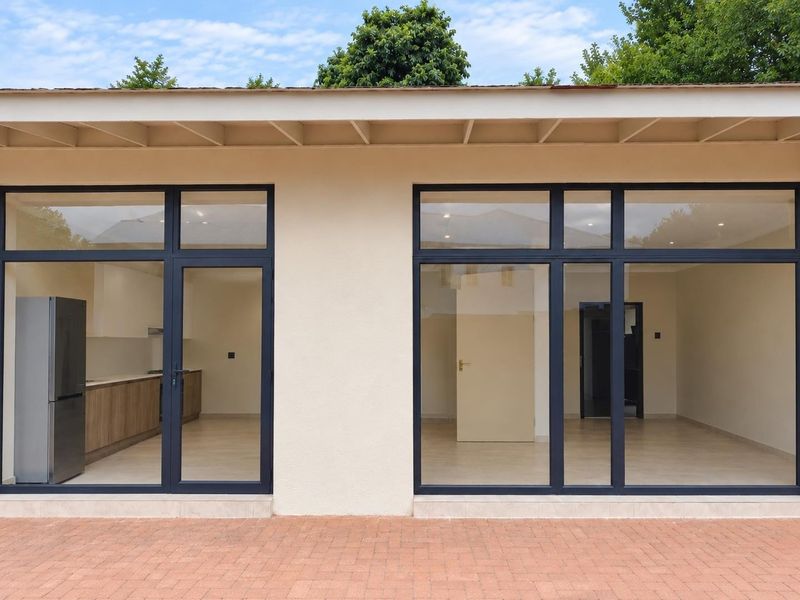 A view of the rear exterior facade featuring modern aluminium framed glass doors opening into the interior living and kitchen spaces.