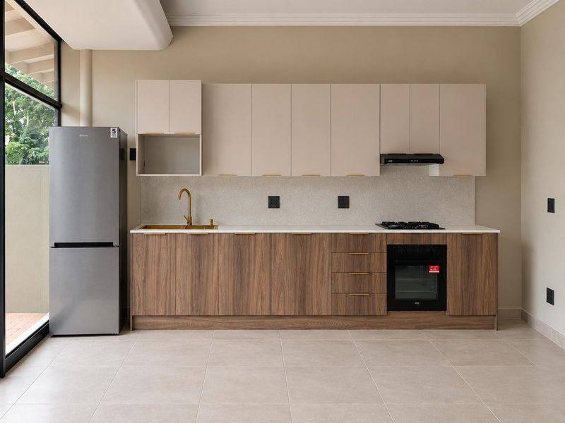 Modern kitchen featuring wood-grain lower cabinetry, neutral upper cabinets, stone countertops, brass fixtures, and integrated appliances in a clean, open-plan space.