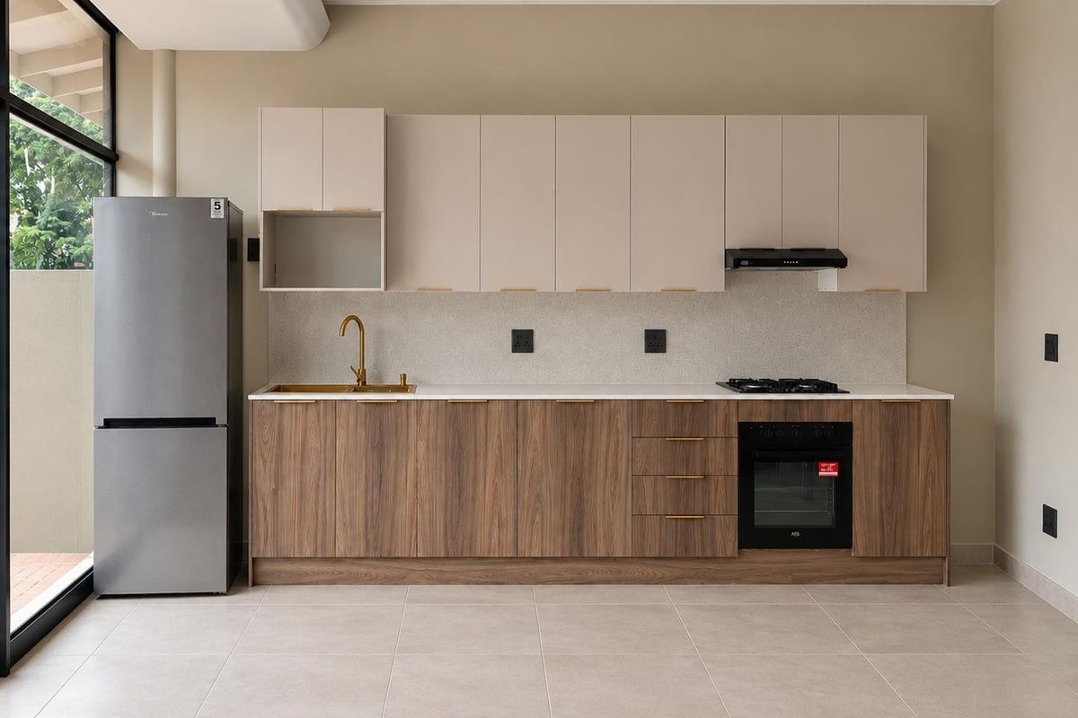 Modern kitchen featuring wood-grain lower cabinetry, neutral upper cabinets, stone countertops, brass fixtures, and integrated appliances in a clean, open-plan space.