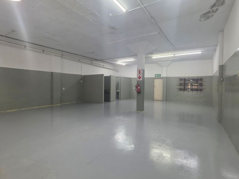 Spacious open-plan industrial unit featuring durable epoxy flooring, fluorescent lighting, and a central structural column, suitable for various commercial or storage applications.