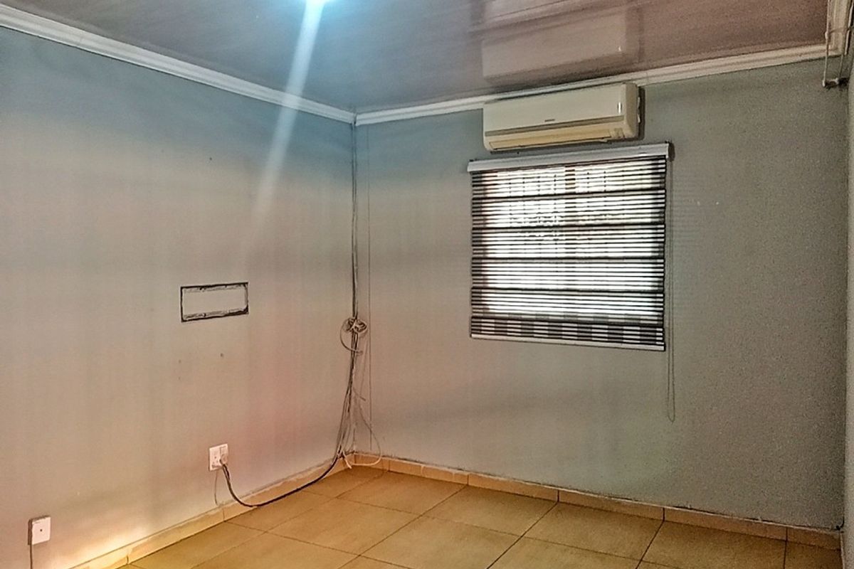 An empty bedroom featuring tiled flooring, an installed air conditioning unit, and window blinds. The space requires minor cosmetic attention to the walls and wiring.