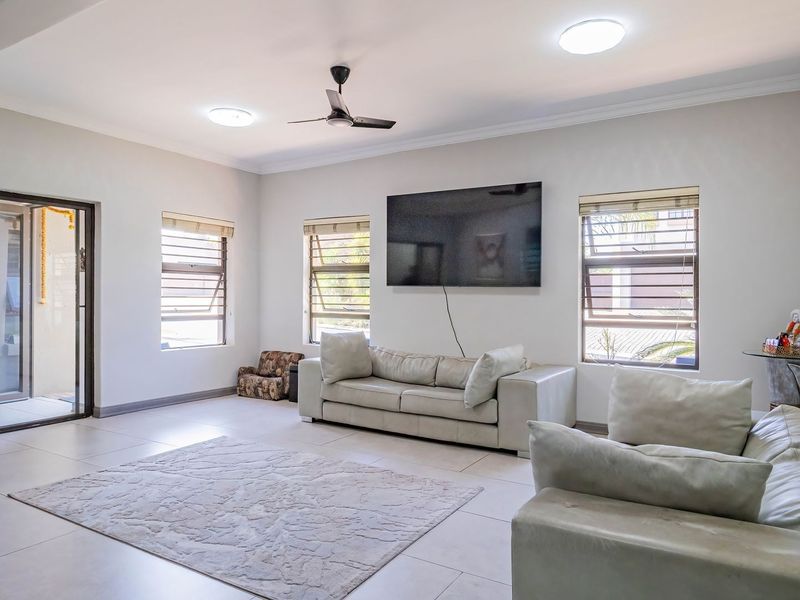 Spacious living room featuring neutral tiled flooring, modern ceiling fan, and large sliding glass doors providing access to the outdoor area.