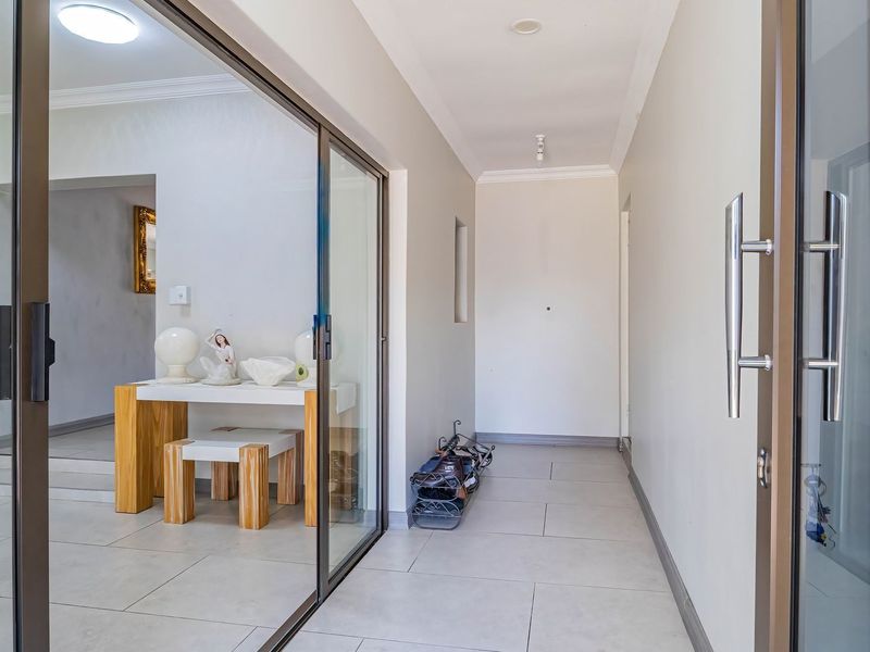 A bright and modern hallway featuring large format floor tiles and sliding glass doors that provide a seamless transition to adjacent living spaces.