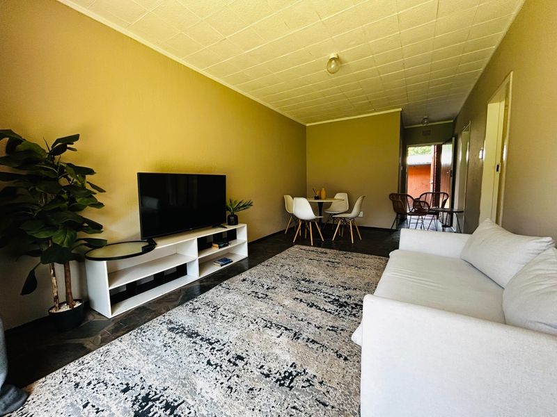 Open plan living and dining area featuring tiled flooring and textured ceiling tiles, providing a functional space for relaxation and meals.