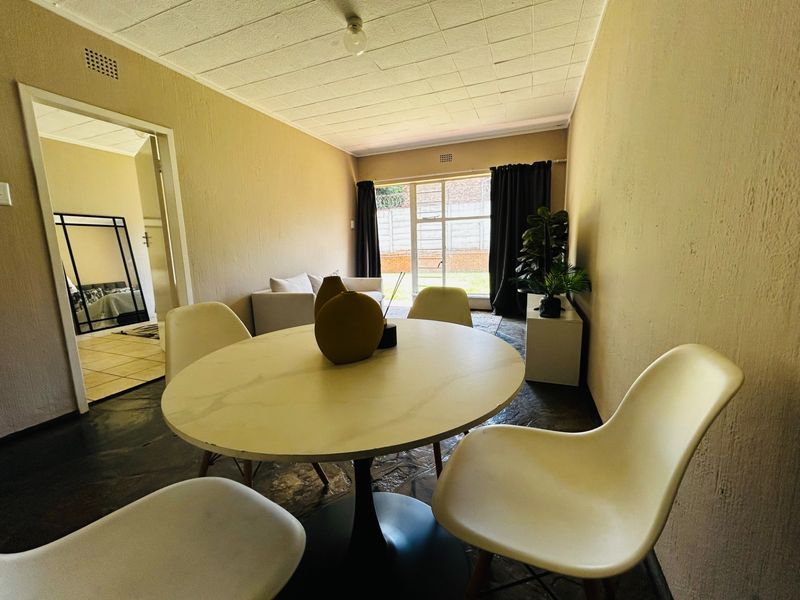 Open plan living and dining area featuring tiled flooring, textured ceiling, and direct access to an outdoor space through a sliding door.