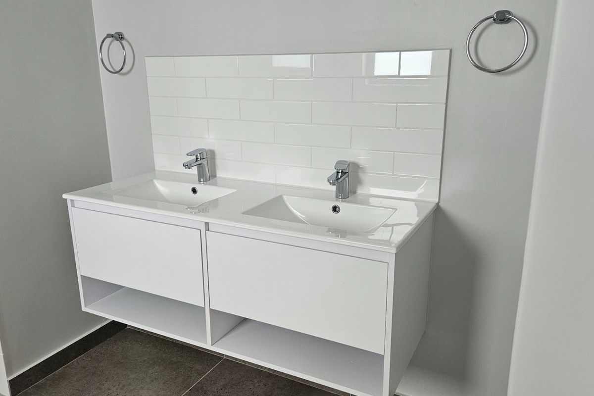 Modern bathroom featuring a clean double vanity with white cabinetry, chrome fixtures, and a classic subway tile backsplash.