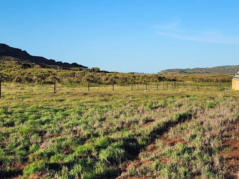 Expansive rural landscape featuring open grazing land, wire fencing, and a water reservoir equipped with solar panels.