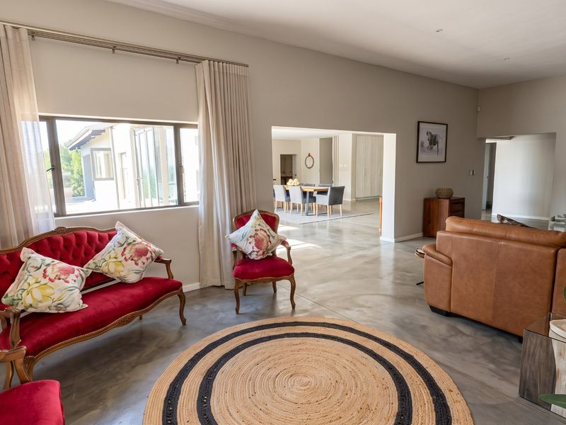 Spacious open-plan living area featuring polished concrete floors, recessed lighting, and seamless flow into the adjacent dining space.