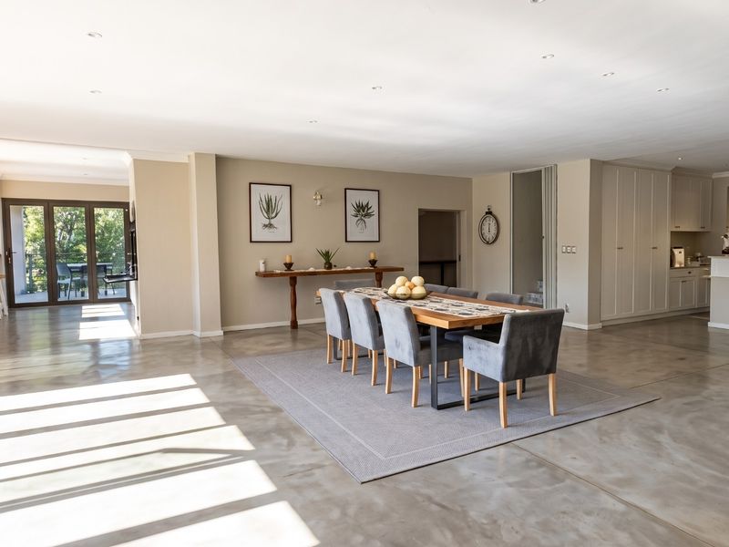 Spacious open-plan living and dining area featuring polished concrete floors, modern built-in cabinetry, and seamless access to the outdoor patio through sliding glass doors.