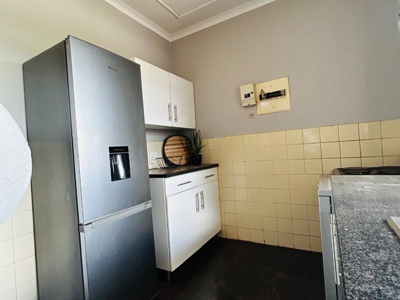 A functional kitchen area featuring built-in cabinetry, granite countertops, and a tiled backsplash, providing a practical workspace with essential fixed infrastructure.