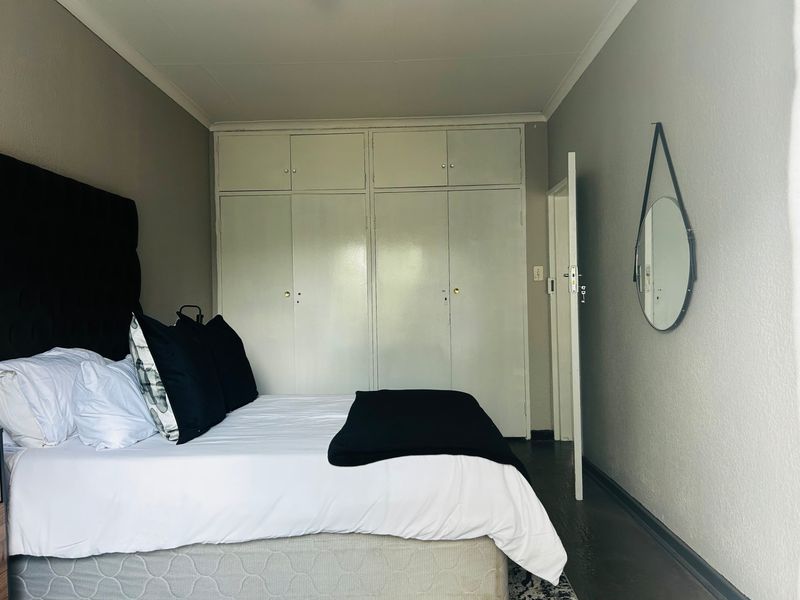 A bedroom featuring built-in cupboards with overhead storage and coved ceiling detailing.