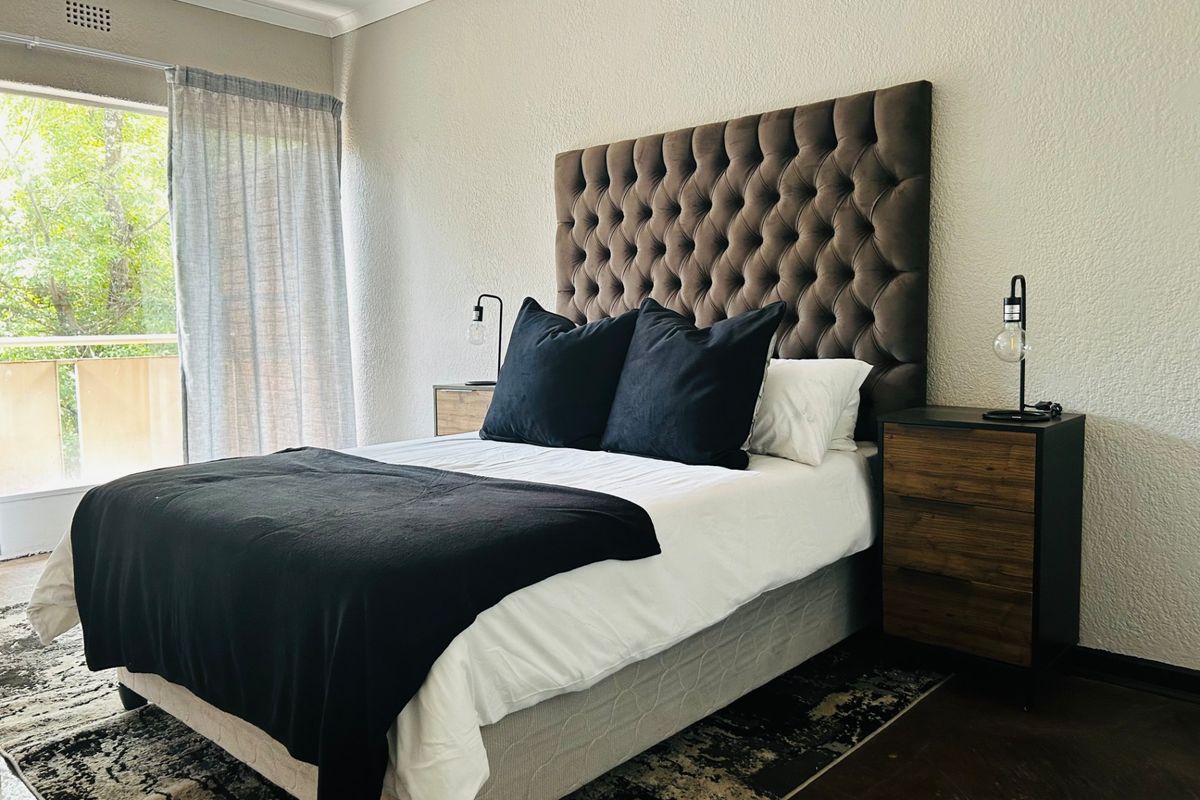 A well-lit bedroom featuring a sliding glass door providing access to a balcony and neutral wall finishes.