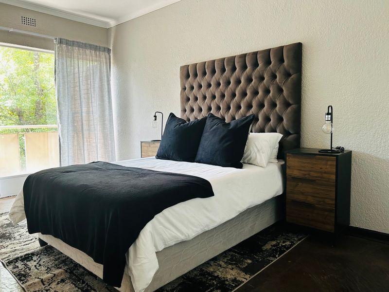 A well-lit bedroom featuring a sliding glass door providing access to a balcony and neutral wall finishes.