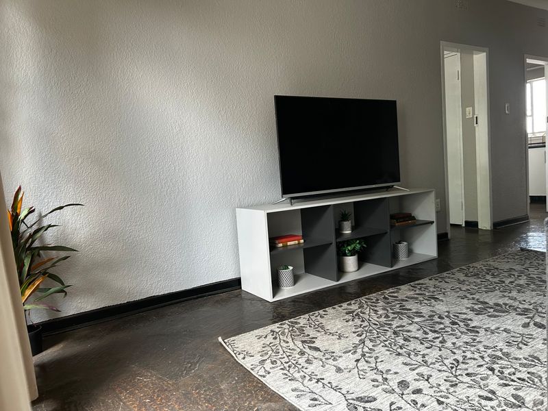 A living room area featuring dark flooring, textured walls, and dark skirting boards, providing a neutral base for interior design.