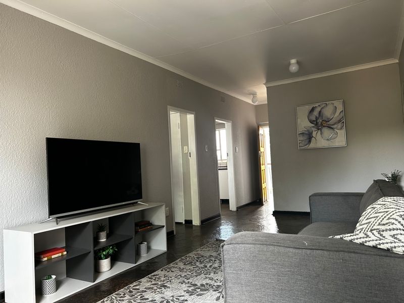 A neutrally painted living room featuring coved ceilings and direct access to the hallway and adjacent rooms.