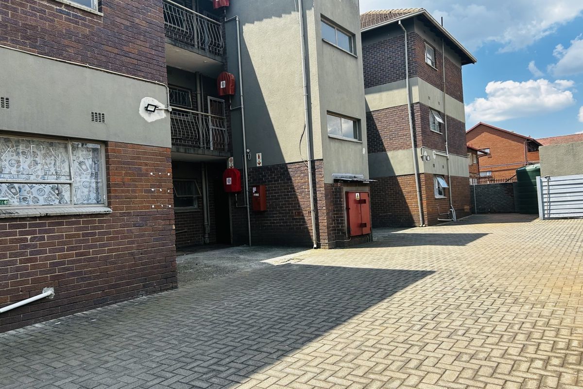 Exterior view of an apartment complex featuring brick facade, paved driveway, and communal fire safety equipment.