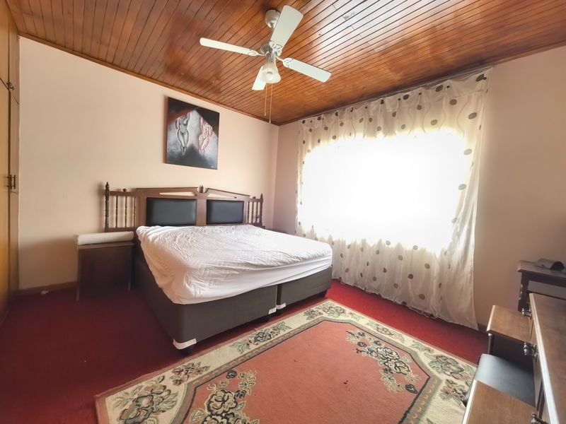 A bedroom featuring a timber tongue and groove ceiling, a ceiling fan, and built-in wardrobe storage.