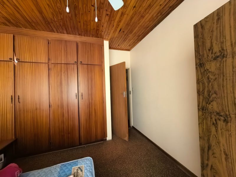 A bedroom featuring extensive built-in wooden cabinetry, a traditional wooden tongue and groove ceiling, and carpeted flooring.