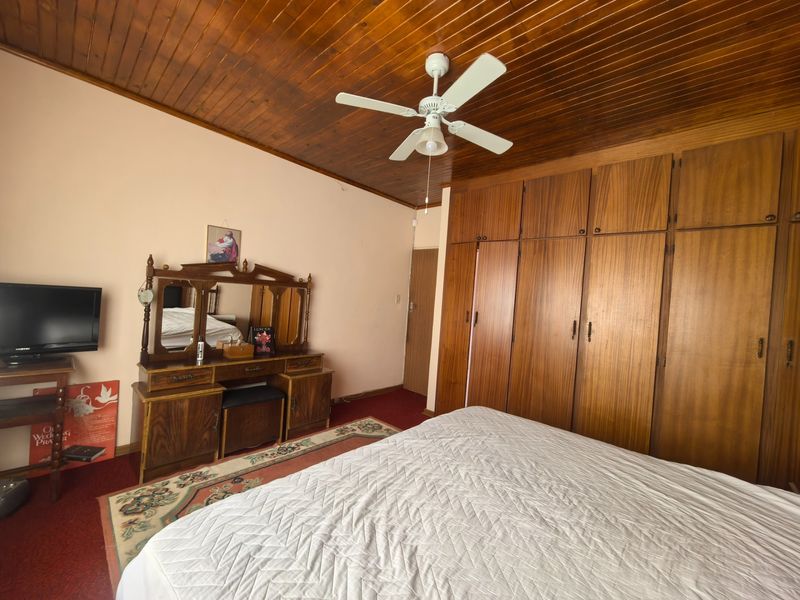 A bedroom featuring extensive built-in wooden cabinetry, a classic wooden tongue and groove ceiling, and a central ceiling fan.