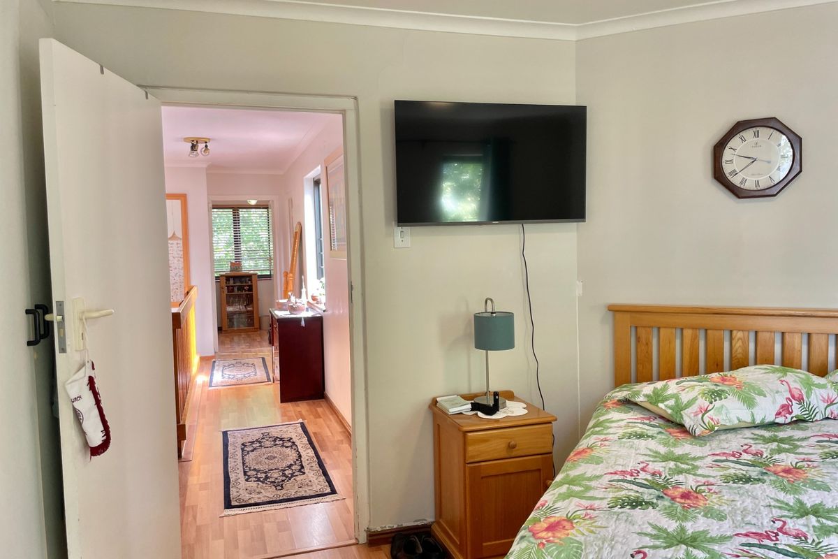 A bedroom featuring laminate flooring and coved ceilings, with a doorway leading to a hallway area.
