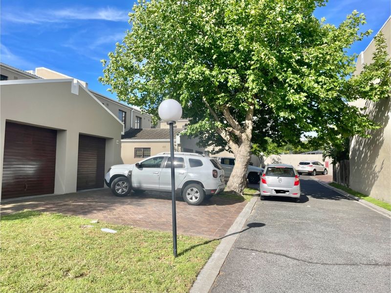 Front exterior view of the townhouse featuring a double garage, paved driveway, and established garden tree.