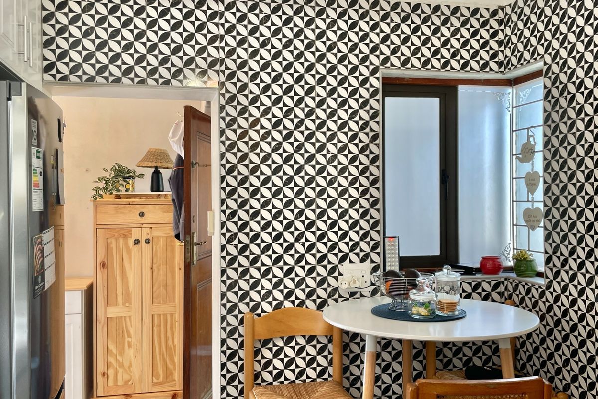 A kitchen breakfast nook area featuring bold patterned wall tiles and a corner window, providing a bright and distinct dining space.