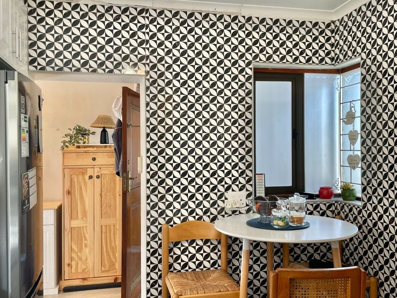 A kitchen breakfast nook area featuring bold patterned wall tiles and a corner window, providing a bright and distinct dining space.