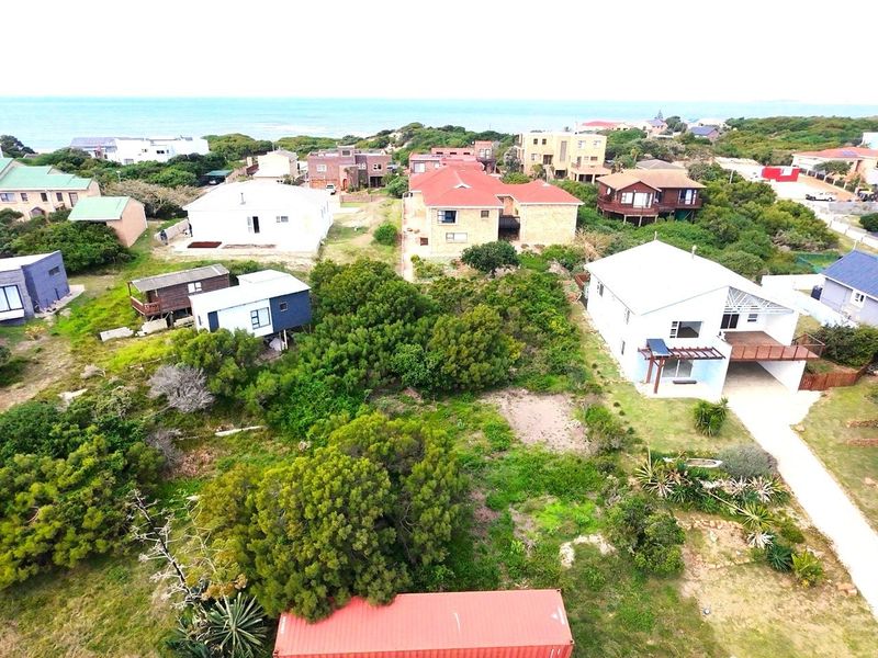 Aerial view of a residential coastal neighborhood featuring vacant land plots surrounded by established homes and native vegetation.
