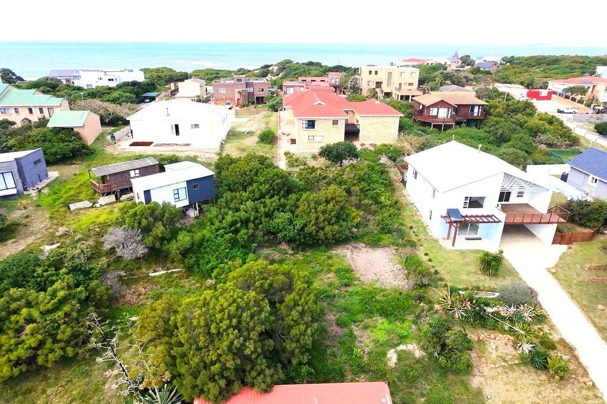 Aerial view of a residential coastal neighborhood featuring vacant land plots surrounded by established homes and native vegetation.