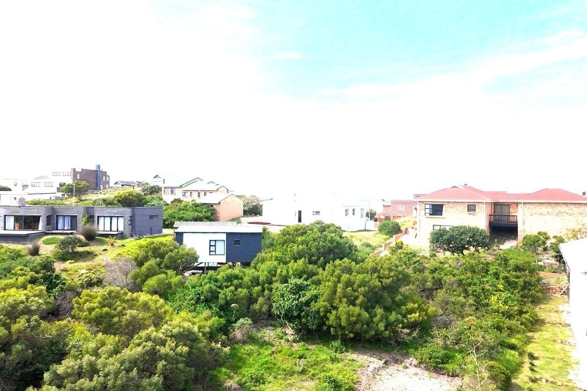 An aerial view of the residential neighborhood showing surrounding properties and established coastal vegetation on the vacant land.