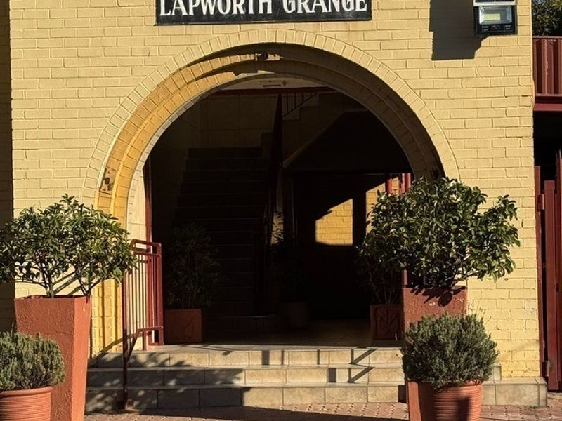 The front entrance of Lapworth Grange features a distinctive arched doorway, brick facade, and paved approach, providing a welcoming and secure building access point.