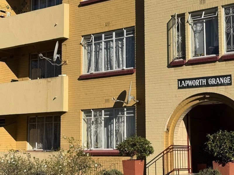 Front elevation of Lapworth Grange apartment building featuring a brick facade, arched entrance, and private balconies.