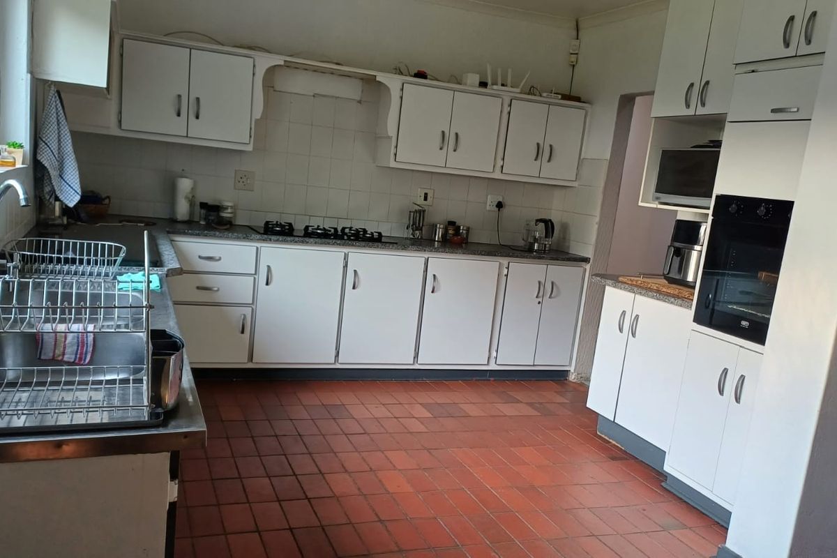 A functional kitchen featuring white built-in cabinetry, a gas hob, built-in oven, and a double sink with tiled flooring and backsplash.