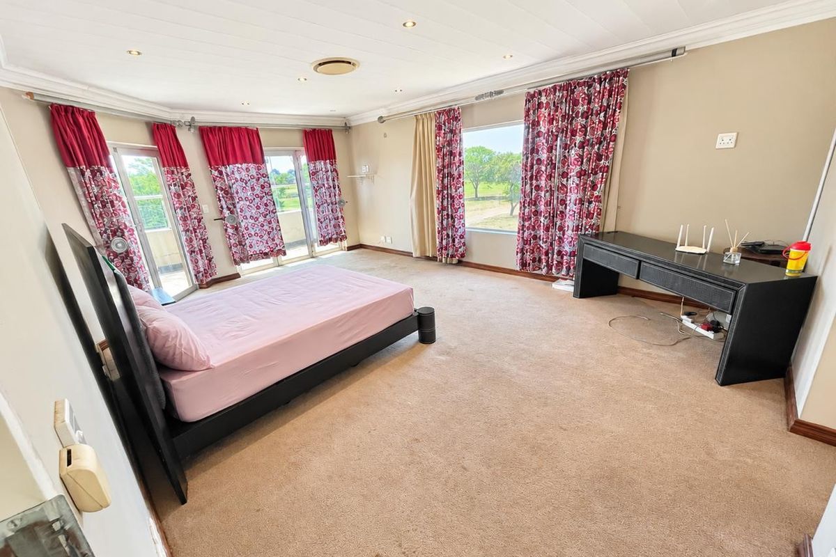 Spacious bedroom featuring carpeted flooring, recessed lighting, and multiple sliding glass doors providing access to an outdoor area with scenic views.