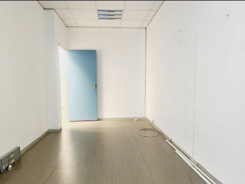 An empty office space featuring a suspended ceiling, recessed lighting, and laminate flooring, ready for customization.
