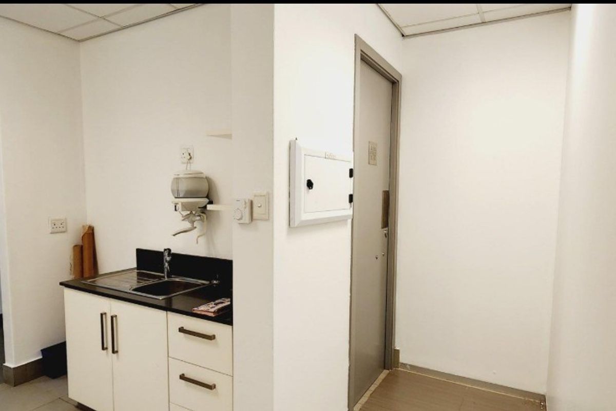 A compact office kitchenette featuring built-in cabinetry, a stainless steel sink, and a drop ceiling, providing essential utility space for the office environment.