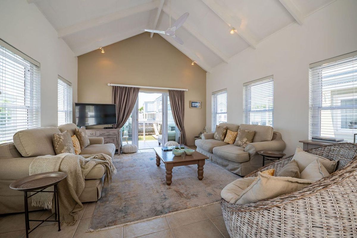 Spacious living room featuring a high vaulted ceiling, ceiling fan, tiled flooring, and large sliding glass doors providing access to the outdoor patio area.