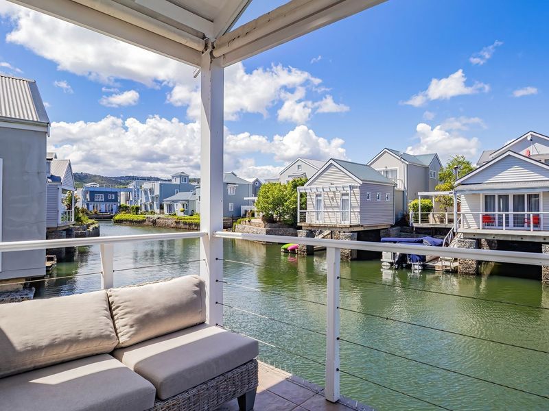 A covered balcony overlooking a canal with views of surrounding waterfront properties.