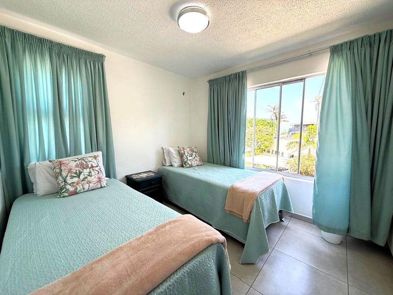 A functional bedroom featuring tiled flooring, a large sliding window providing natural light, and a central ceiling light fixture.