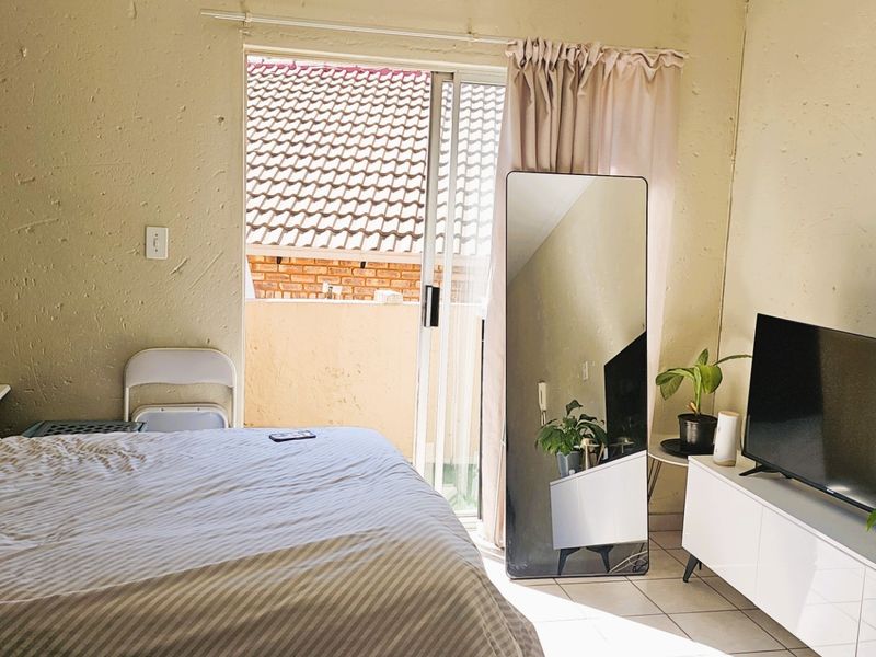 A bedroom featuring tiled flooring and a sliding glass door providing access to an outdoor area, with textured wall finishes throughout.