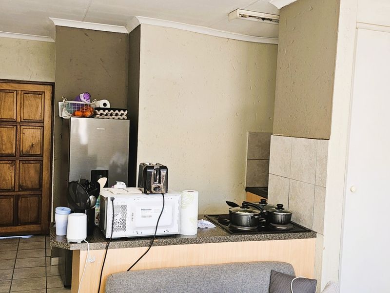 Compact kitchen area featuring a built-in hob, stone countertops, tiled splashback, and tiled flooring, offering a functional layout for daily meal preparation.
