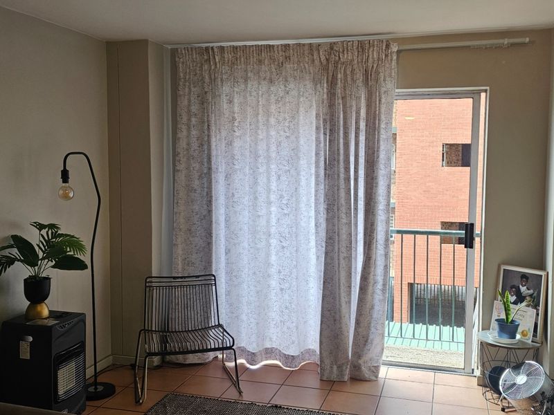 A living room area featuring tiled flooring and a sliding glass door providing direct access to a balcony.