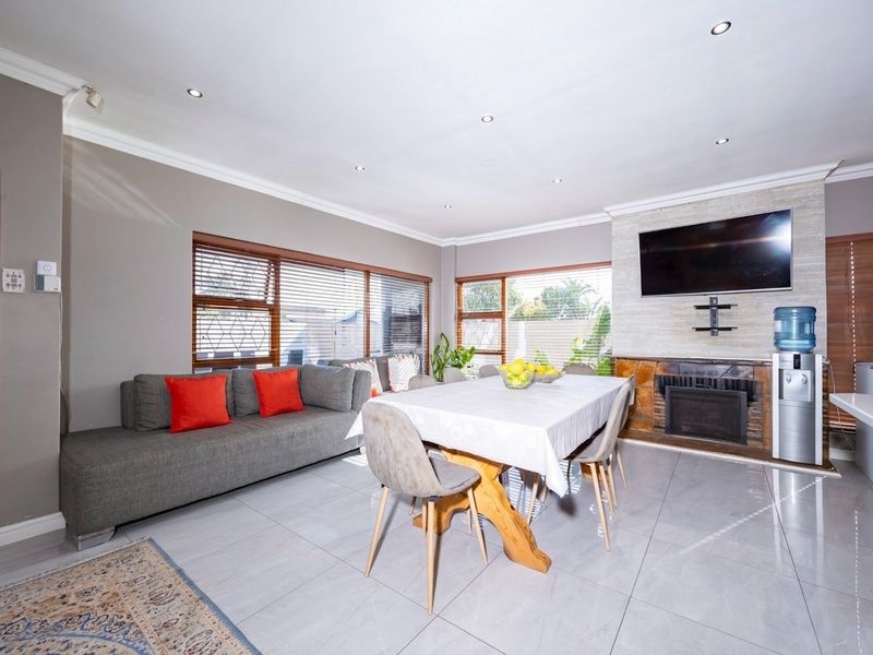 Spacious open-plan living and dining area featuring tiled floors, recessed lighting, and a prominent stone-clad fireplace as a central focal point.