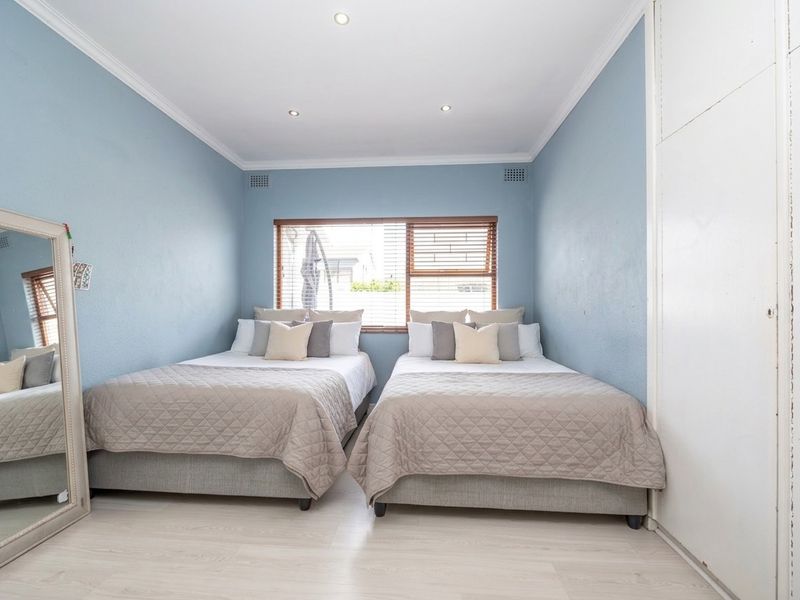 A well-maintained bedroom featuring built-in cupboards, recessed downlighting, and neutral flooring, offering a clean and functional living space.