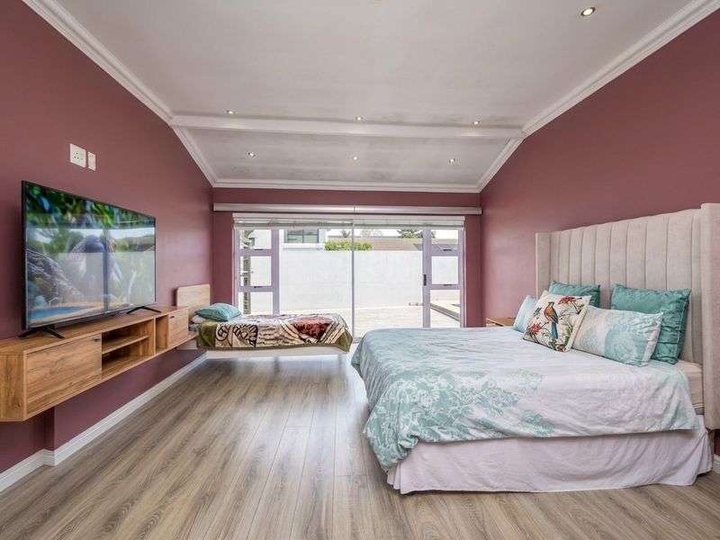 Spacious bedroom featuring modern laminate flooring, recessed lighting, crown molding, and large sliding glass doors providing access to the exterior.