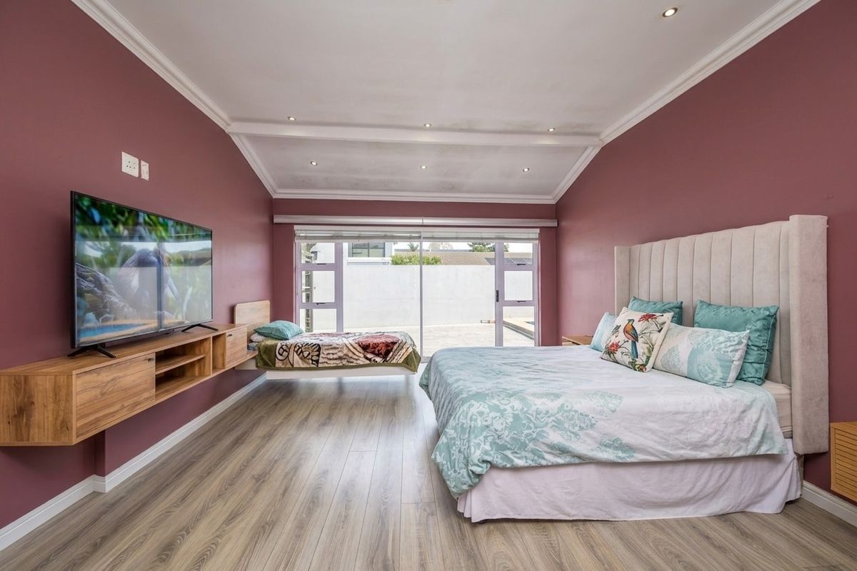 Spacious bedroom featuring modern laminate flooring, recessed lighting, crown molding, and large sliding glass doors providing access to the exterior.
